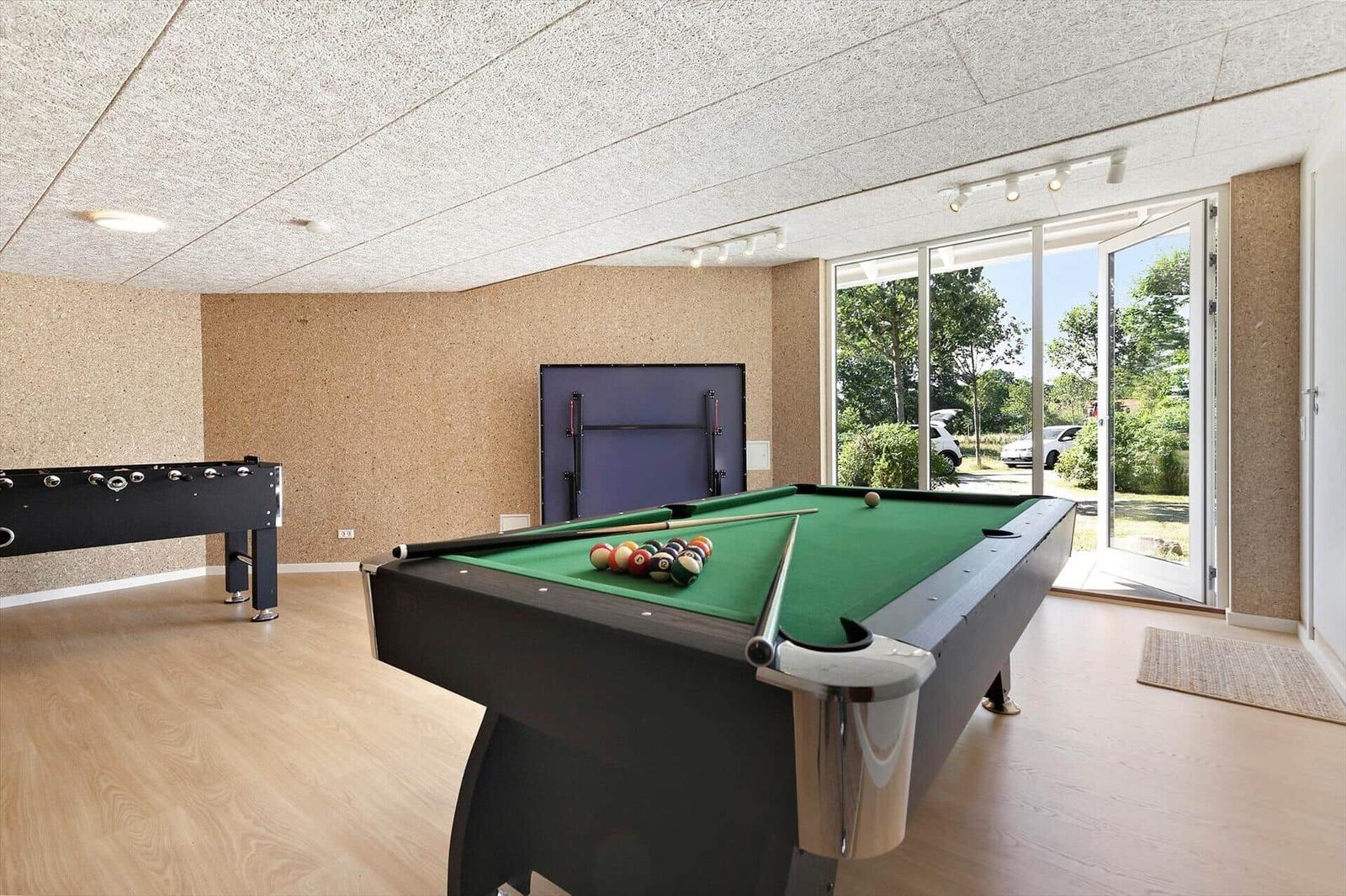 Raum mit Billardtisch, Foosballtisch und Glasfront zur Außenterrasse.