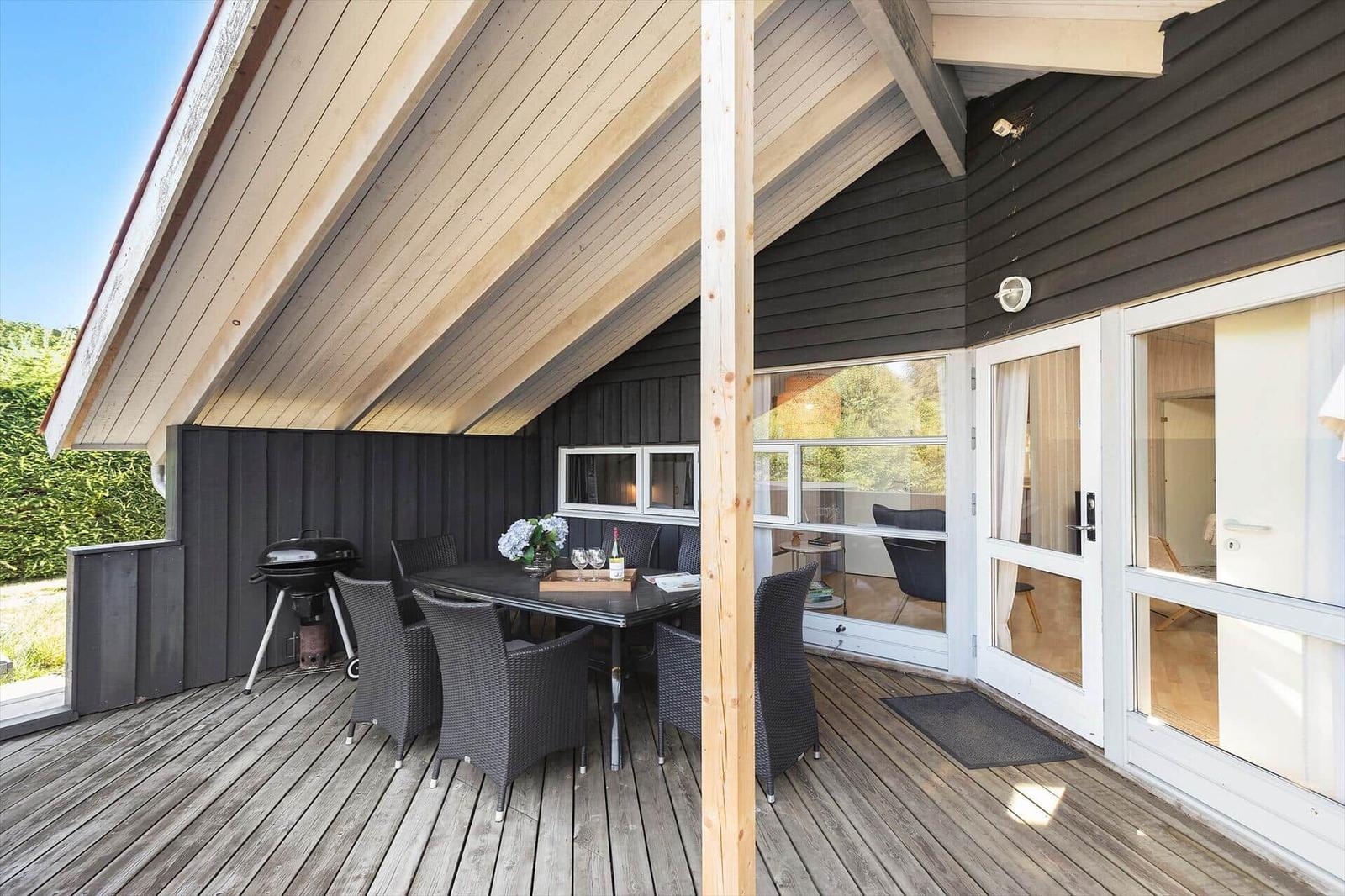 Terrasse mit Essbereich, Grill und Blick in das Haus.