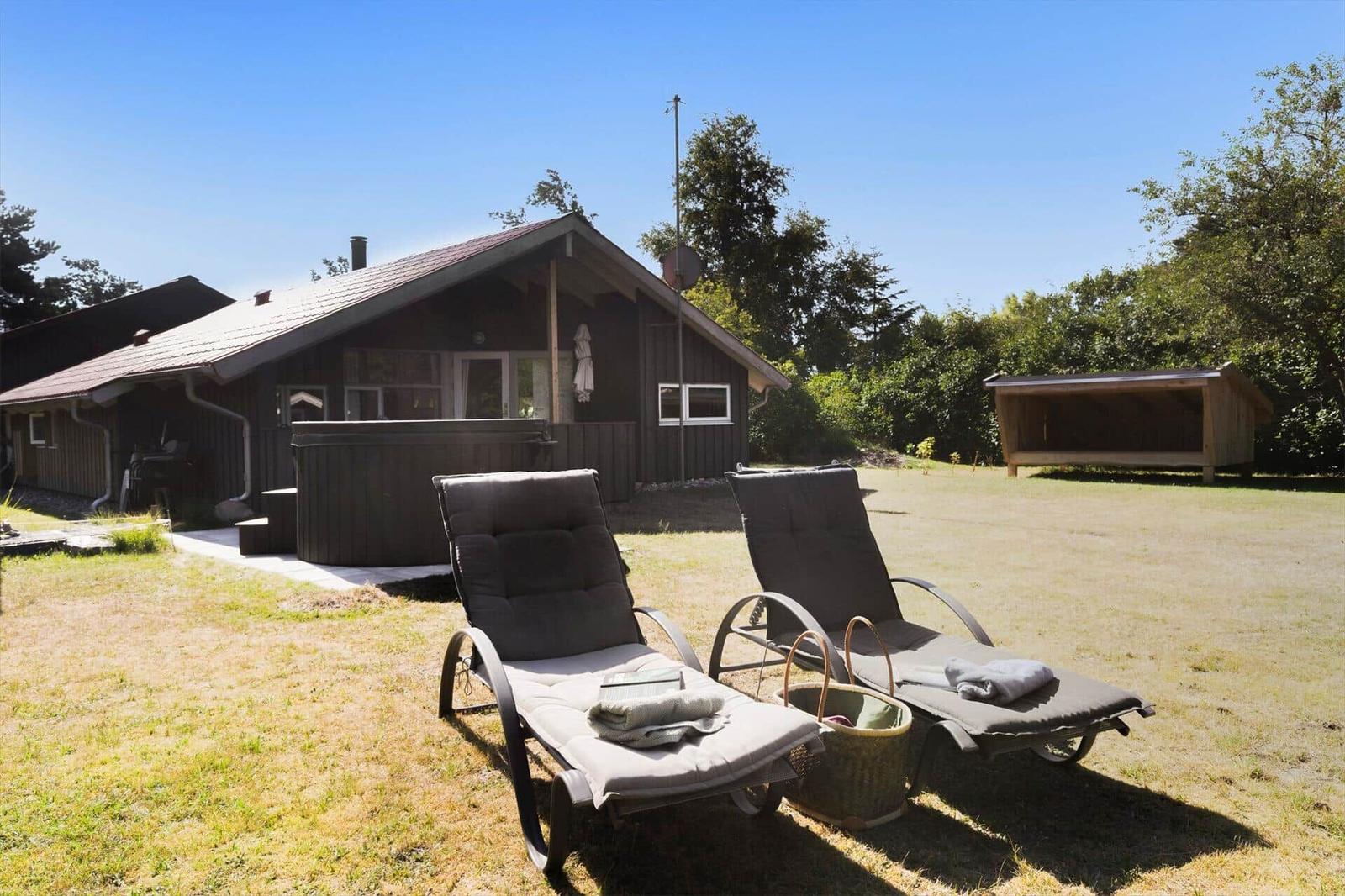 Haus mit Whirlpool, Sonnenliegen und Grünfläche im Freien.