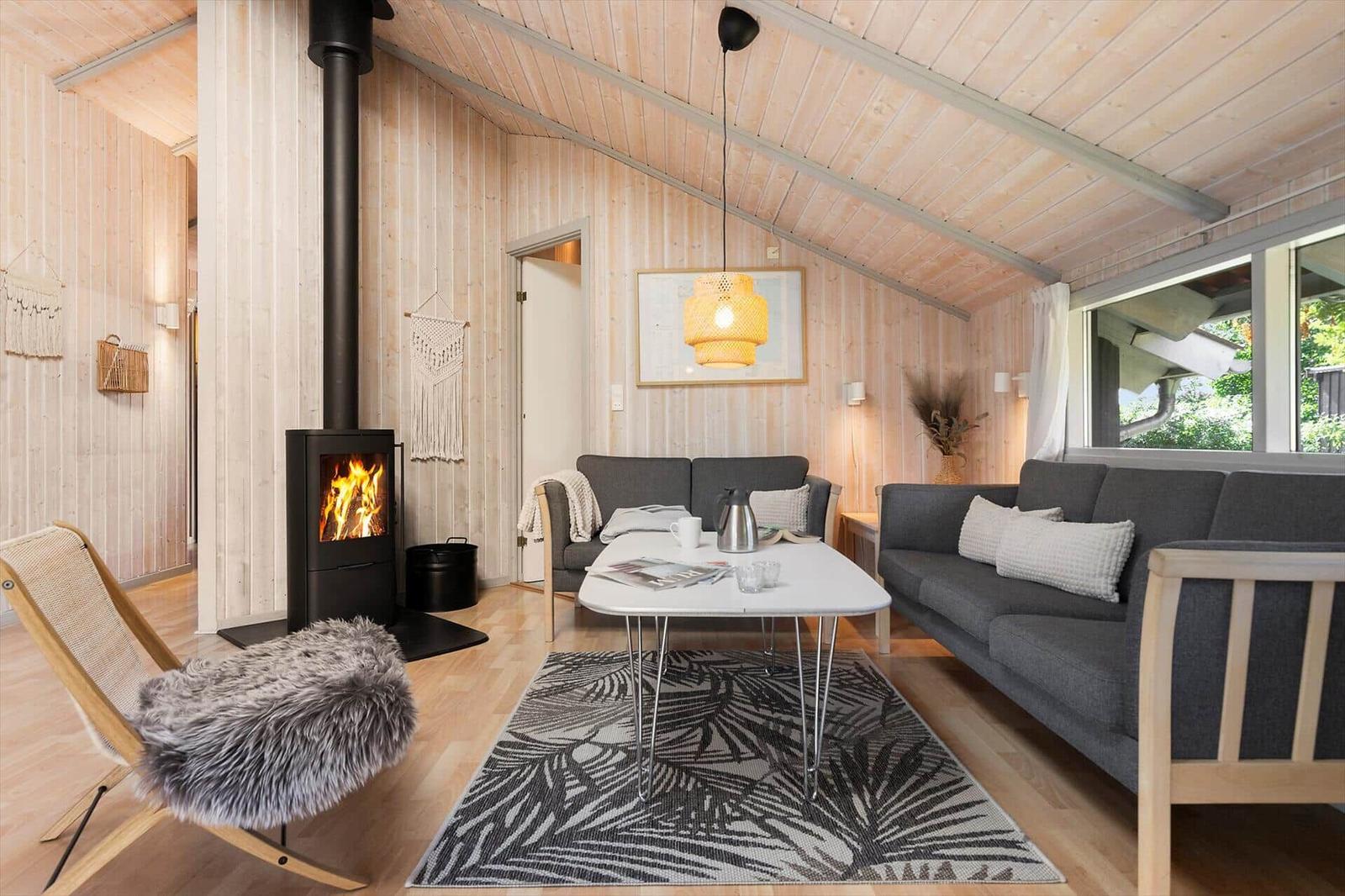 Wohnraum mit Kamin, zwei Sofas und Tisch auf Teppich. Holzwände und Decke.