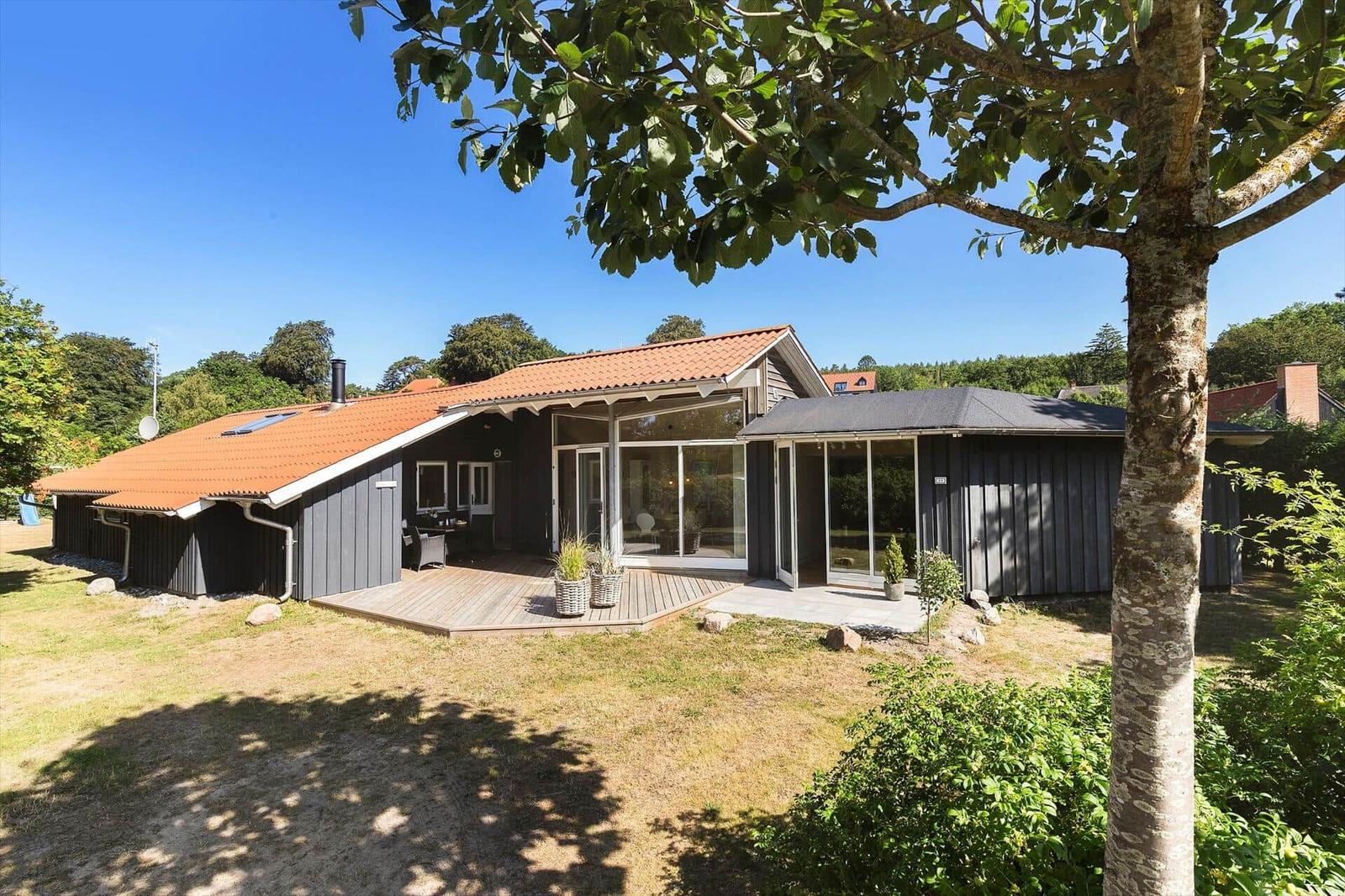 Modernes Ferienhaus mit Holzterrasse und großzügigem Glasbereich im Grünen.