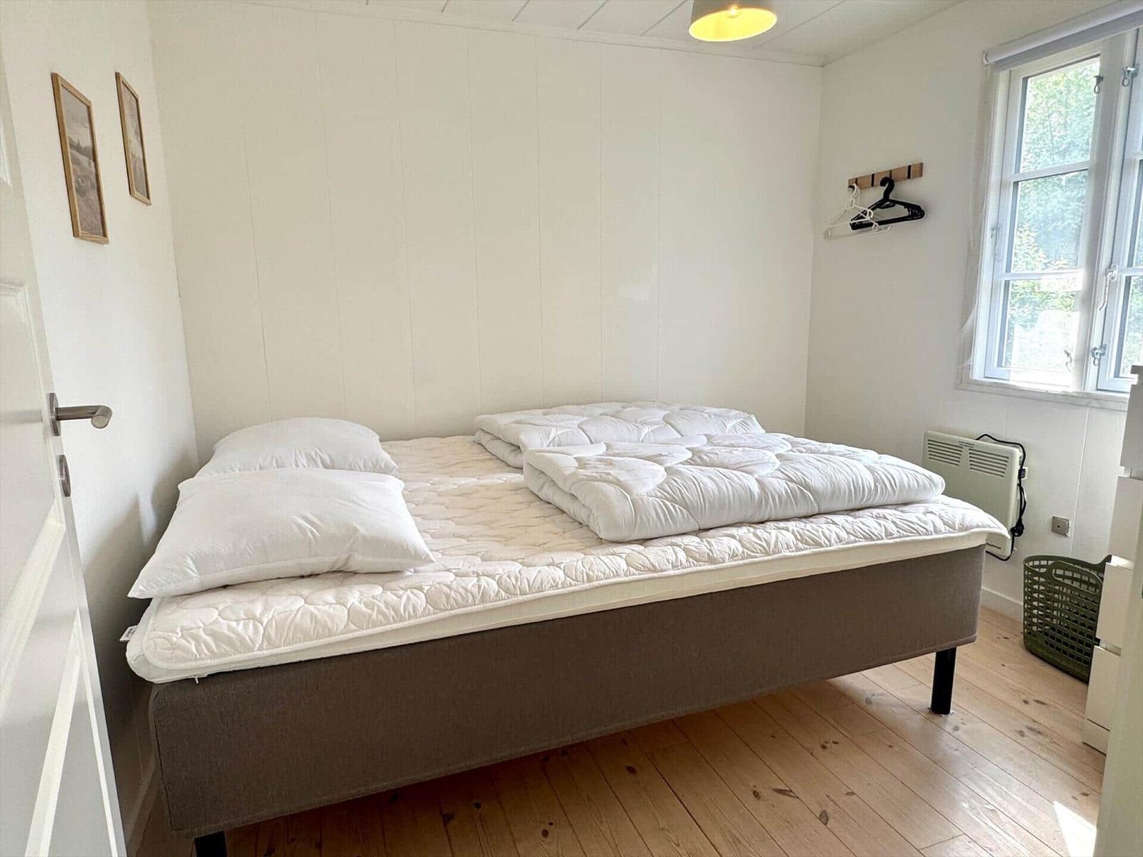 A bedroom with a bed, a window, and a heater.