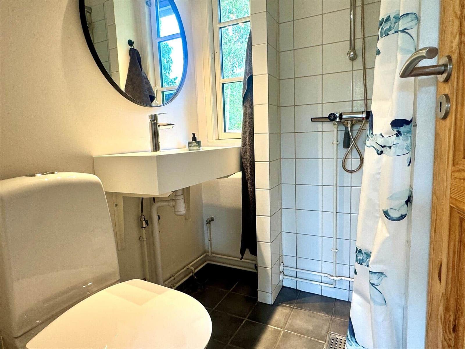 Bathroom with toilet, sink, and shower with shower curtain.