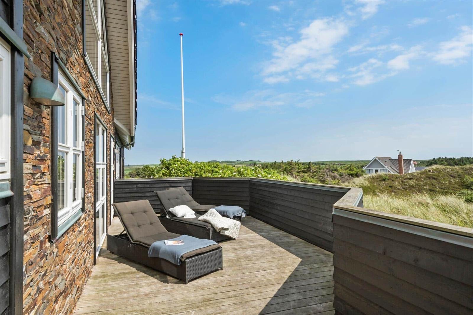 Terrasse mit Liegestühlen und Blick auf die Landschaft.