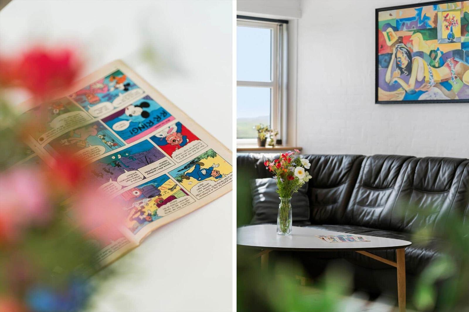 Ein Comic liegt auf einem Tisch. Im Hintergrund ist ein schwarzes Sofa und ein Fenster zu sehen.