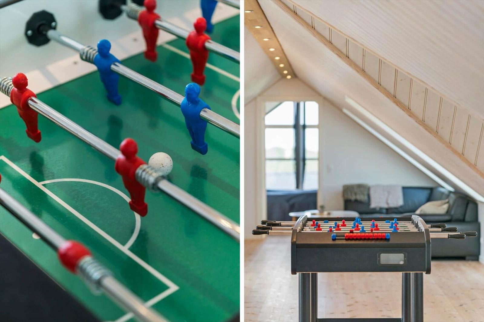 Tischfußballtisch in einem hellen Raum mit Holzdecke und Sofa im Hintergrund.