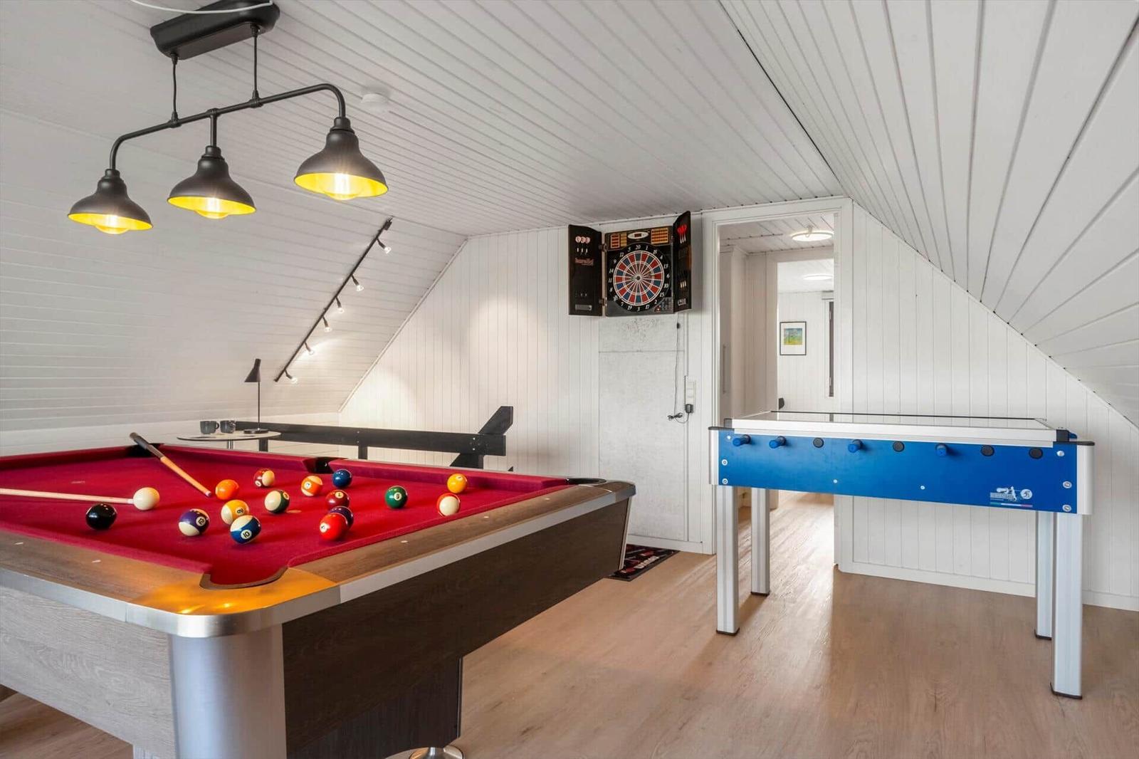 Spielzimmer mit Billardtisch, Dartboard und Tischfußball.