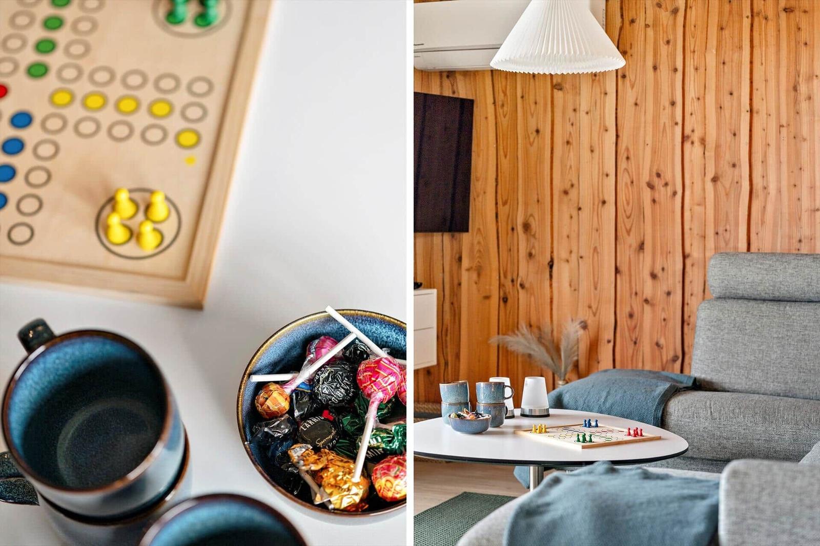 Wohnzimmer mit Holzwand, Sofa und Tisch mit Spiel und Süßigkeiten.