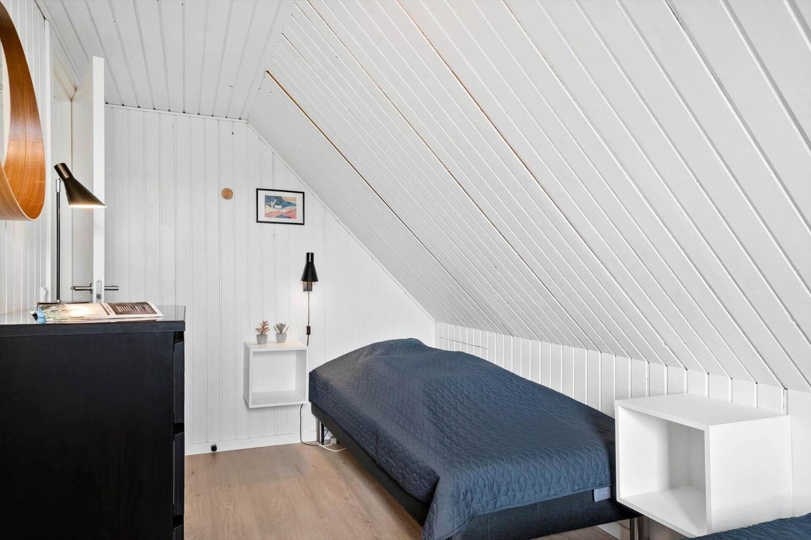 Schlafzimmer mit Dachschrägen, Bett, Nachttisch und Schrank.