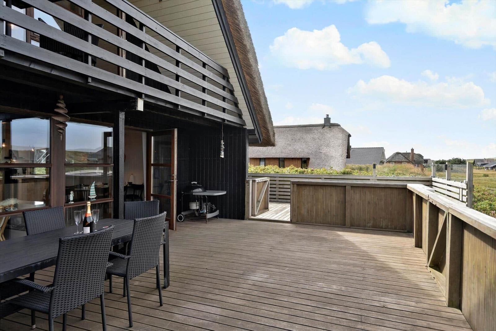 Terrasse mit Tisch, Stühlen und Grill. Blick auf traditionelle Dächer und Felder.
