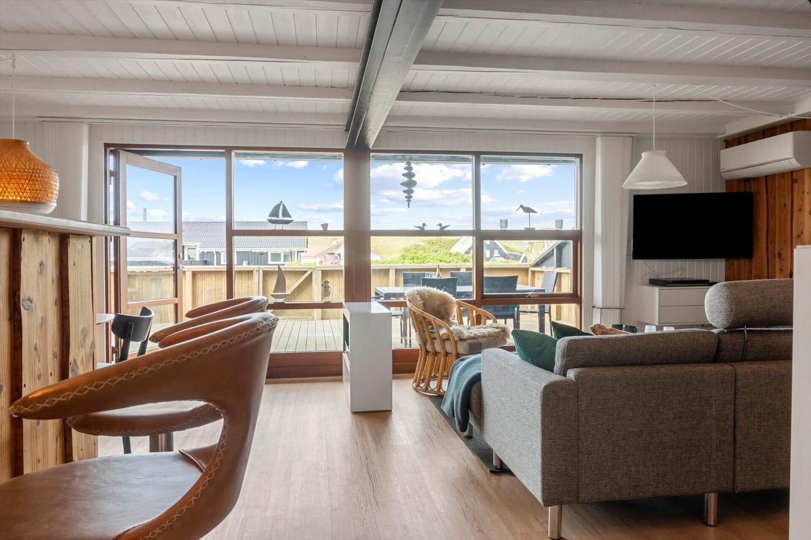 Wohnbereich mit Sofa, Sitzgruppe und großem Fenster zum Balkon.