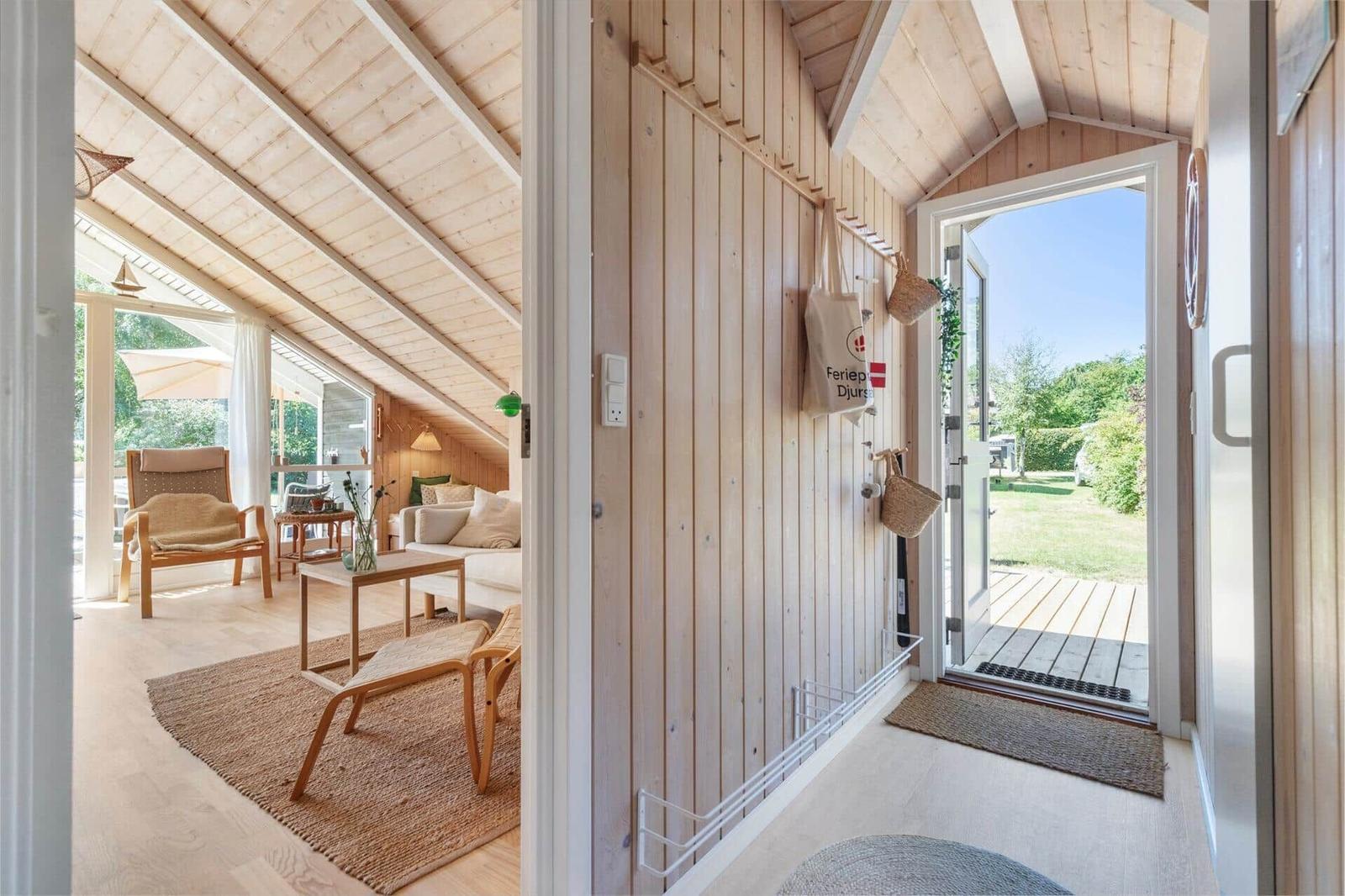 Haus mit Holzwand, Tür zum Garten und Wohnbereich mit Sofa und Stühlen.
