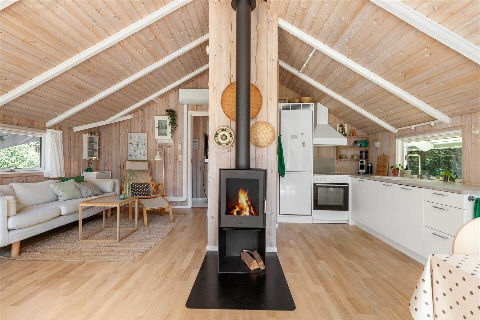 Wohnküche mit Holzdecke, Kaminofen und weißer Küchenzeile.