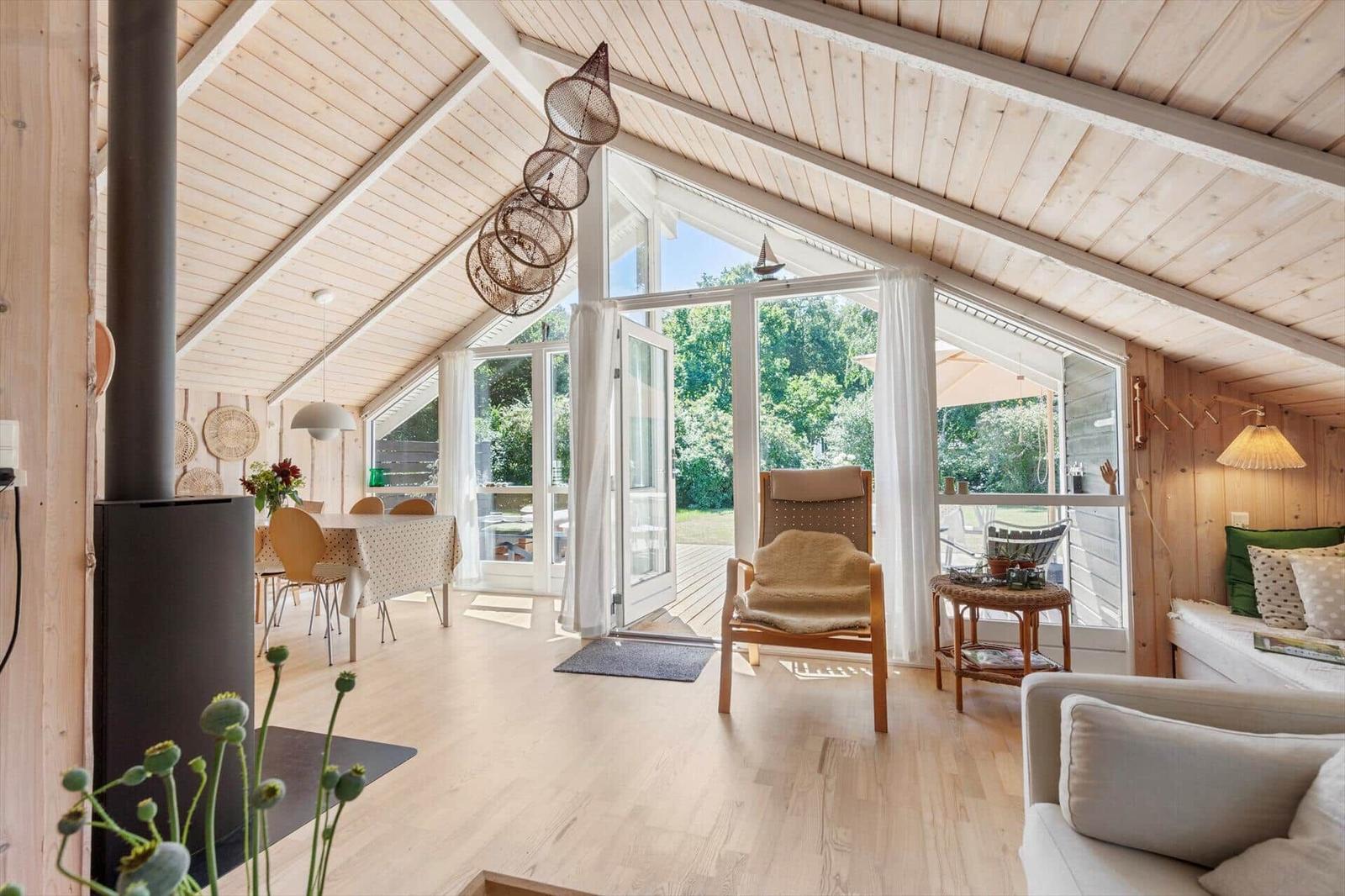 Wohnraum mit Holzdecke, großem Fenster und Sitzgelegenheiten.