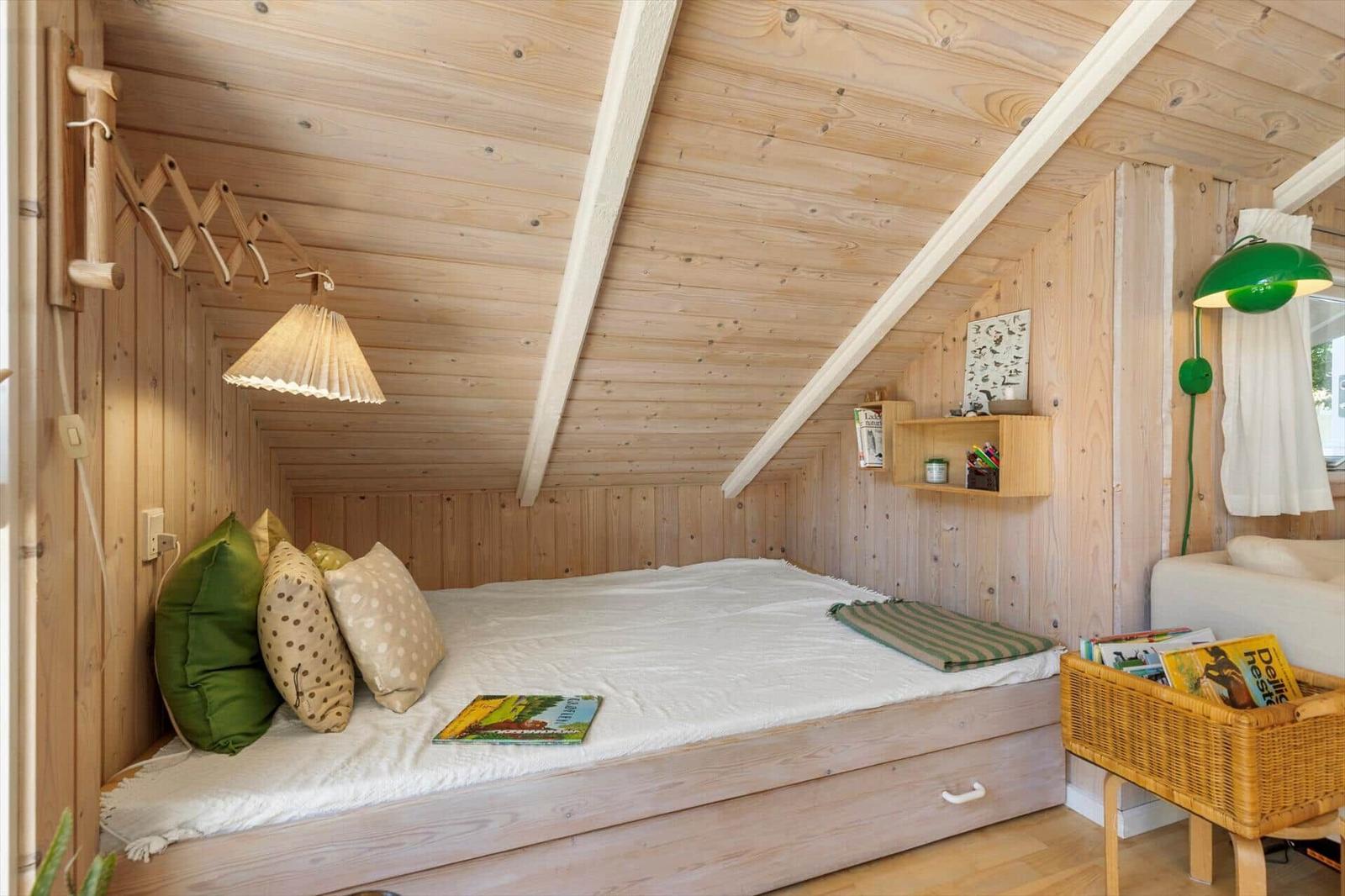 Schlafzimmer mit Holzwand, Bett und grüner Stehlampe.