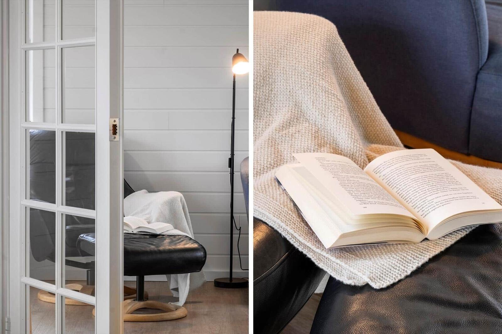 A room with white walls, a black chair, and a floor lamp. A book rests on a cover.
