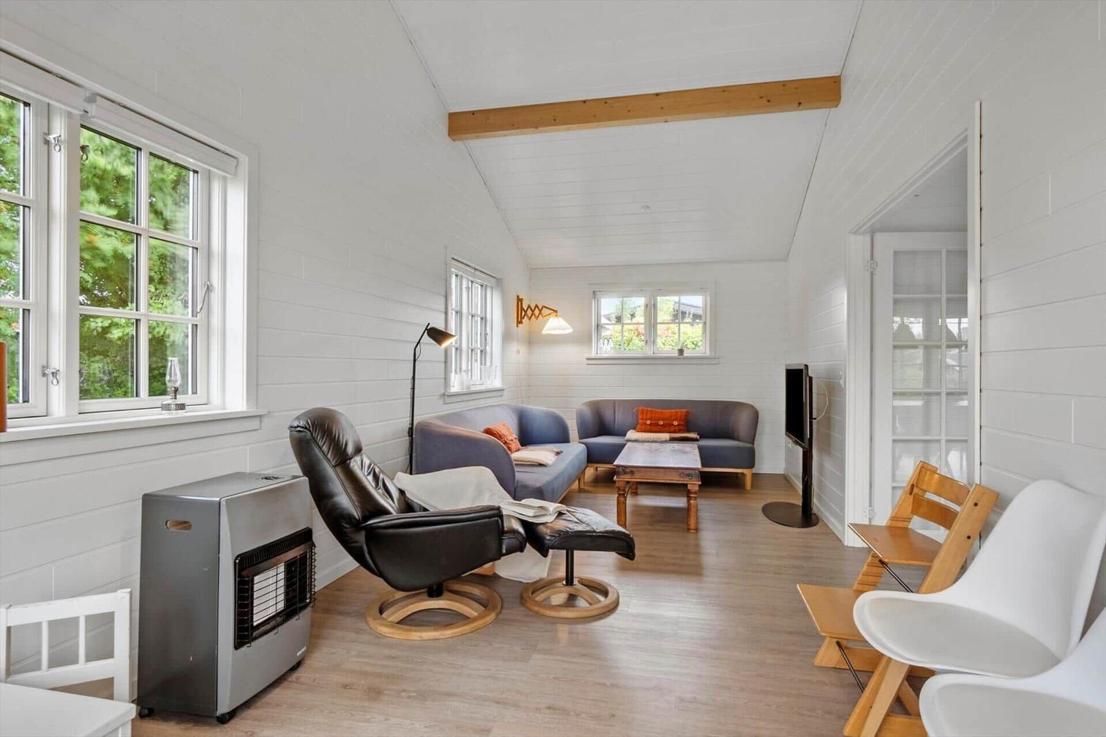 Living room with sofa, chair, and table. Wooden floor and white walls.