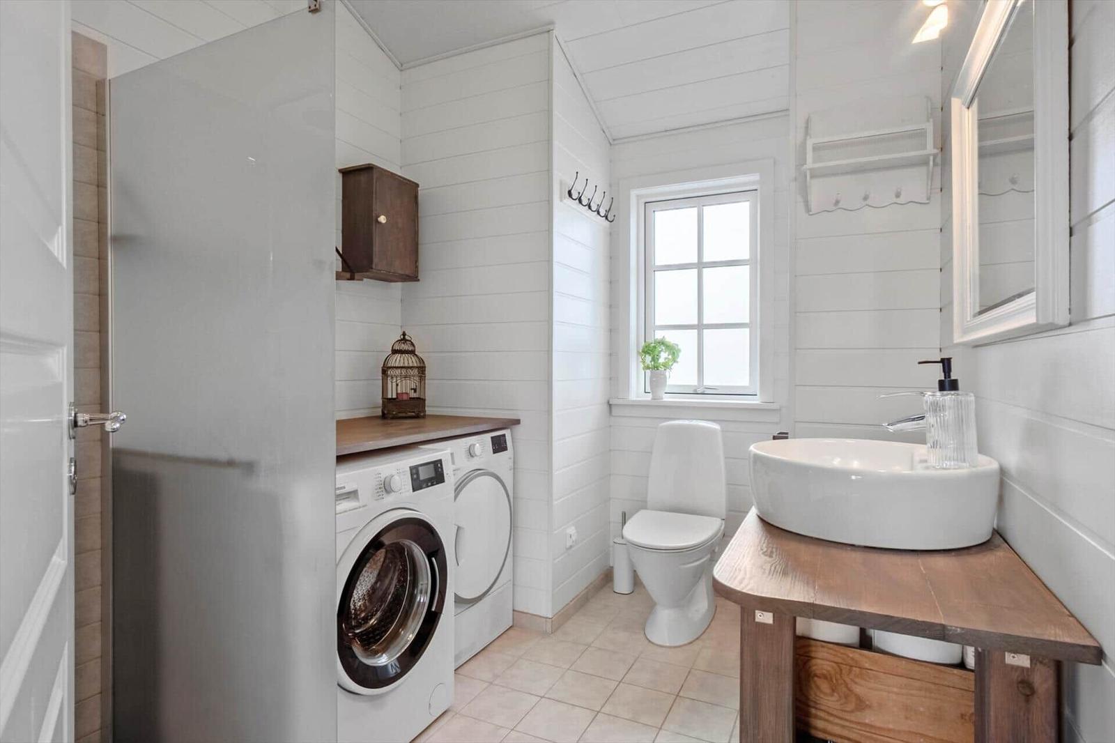 Bathroom with washing machine, toilet, and sink with mirror.