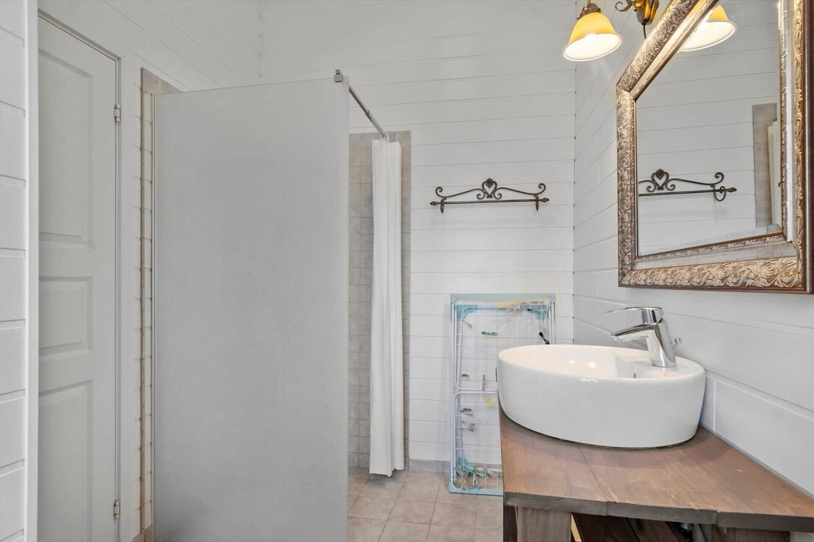 Bathroom with sink, mirror, and shower.