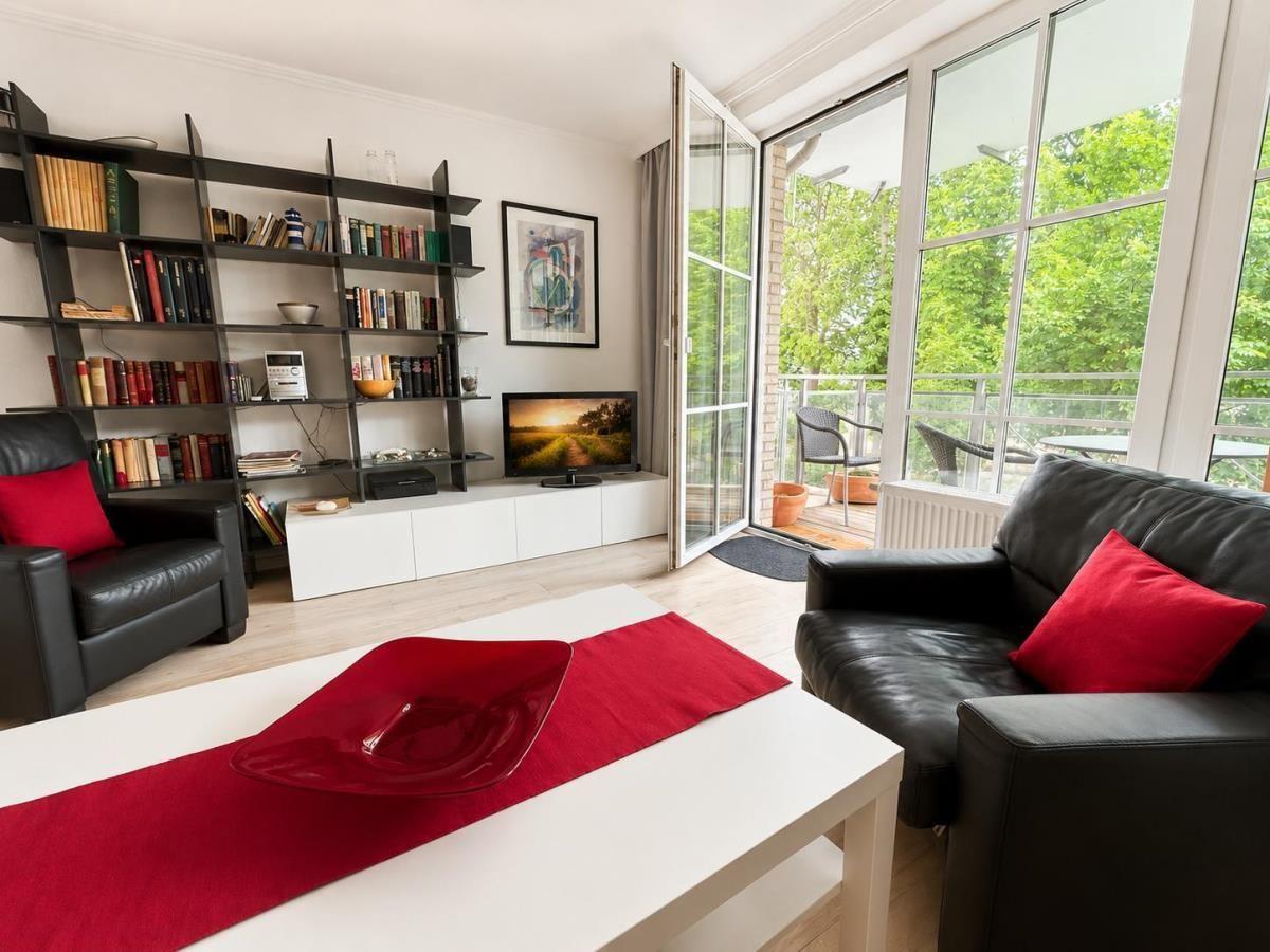 Living room with black leather furniture, bookshelf, and balcony view.