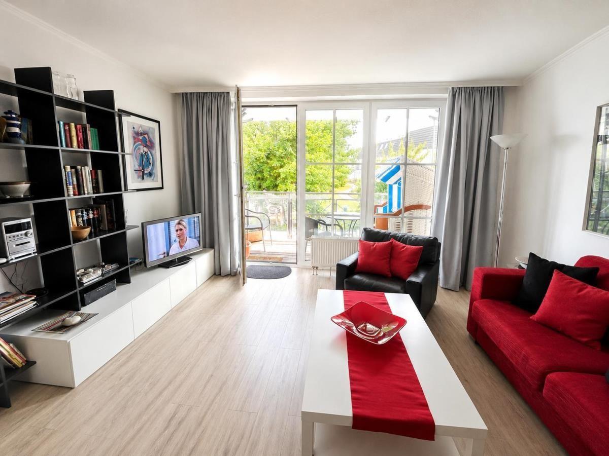 Living room with red sofa, black leather couch, and balcony with garden view.
