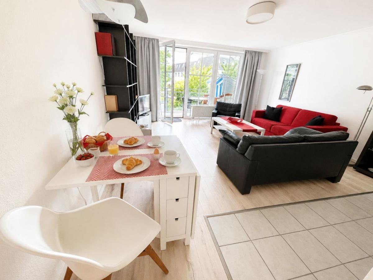 Living and dining area with red sofa, black chairs, and breakfast table.