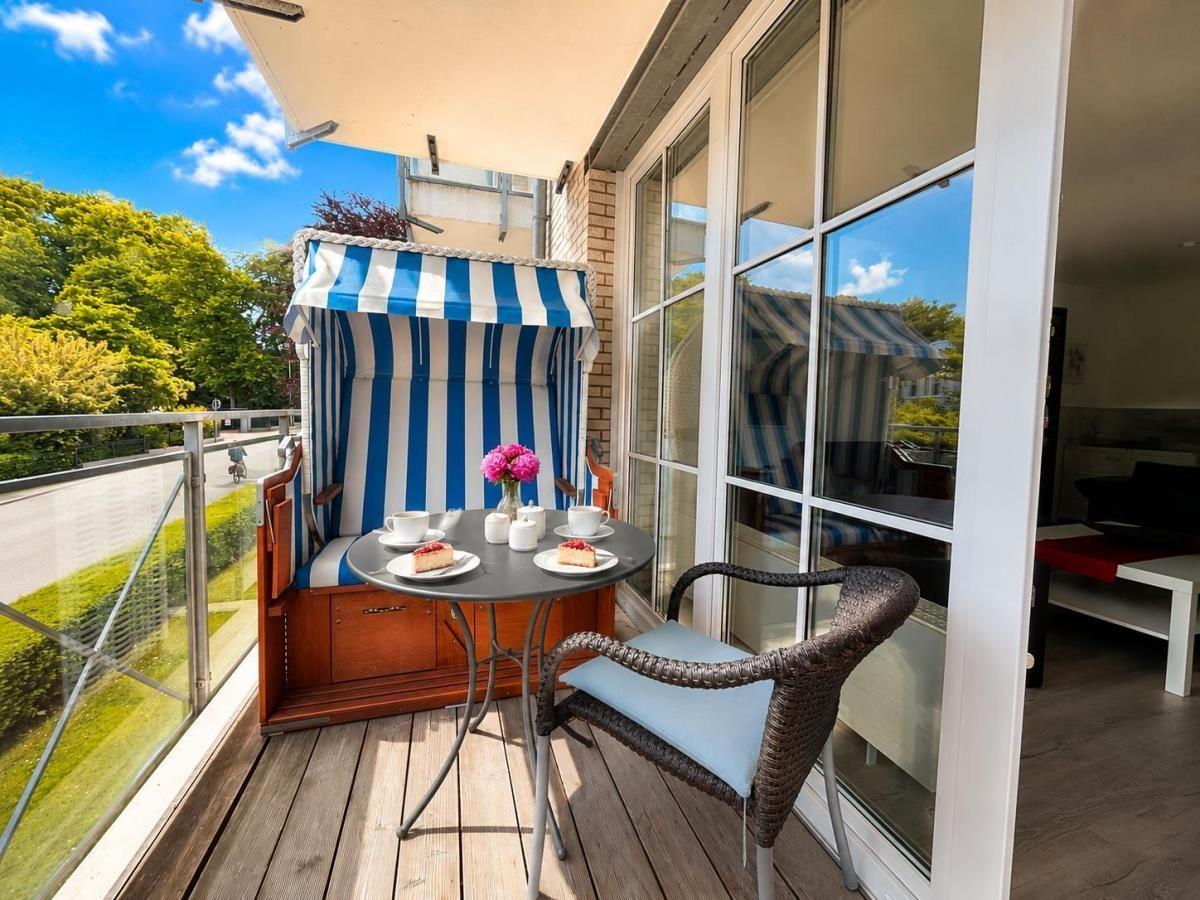 Balcony with striped awning, table, chairs, and view of greenery.