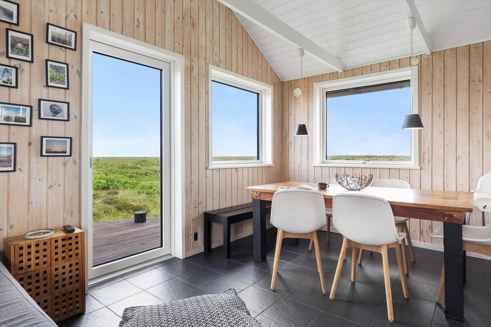 Essbereich mit Tisch, Stühlen und Blick auf Grasland.