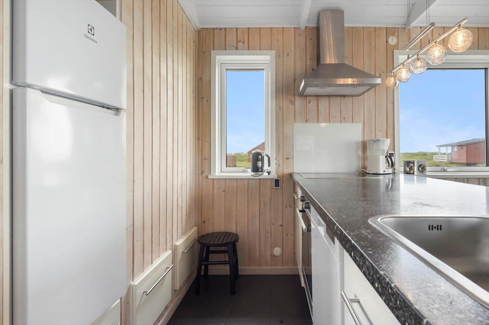 Küche mit Holzwänden, Kühlschrank, Arbeitsplatte und Fenster mit Blick.