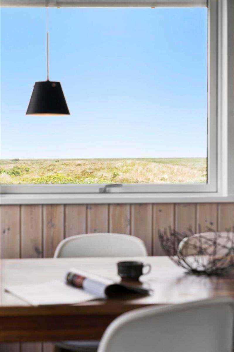 Essbereich mit Tisch, Stühlen und Blick auf Feld unter blauem Himmel.