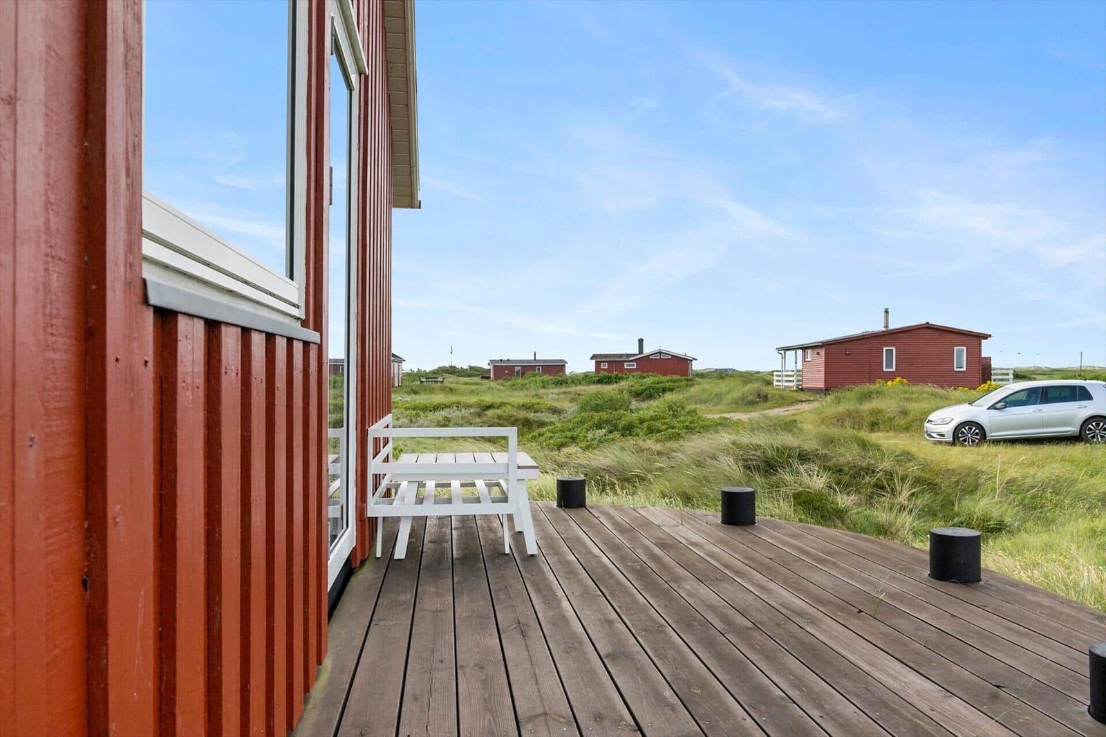 Terrasse mit weißem Stuhl und Blick auf rote Häuser und Grasland.