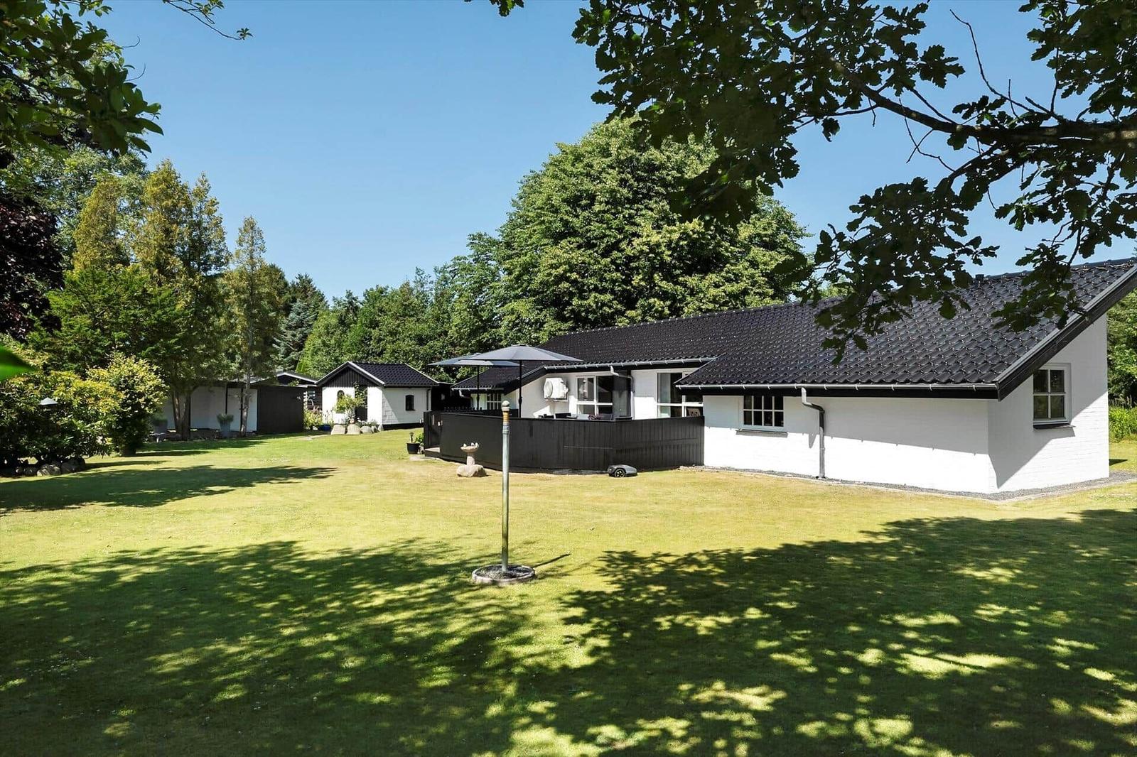Wohnhaus mit Garten und Sonnenschirm unter Bäumen