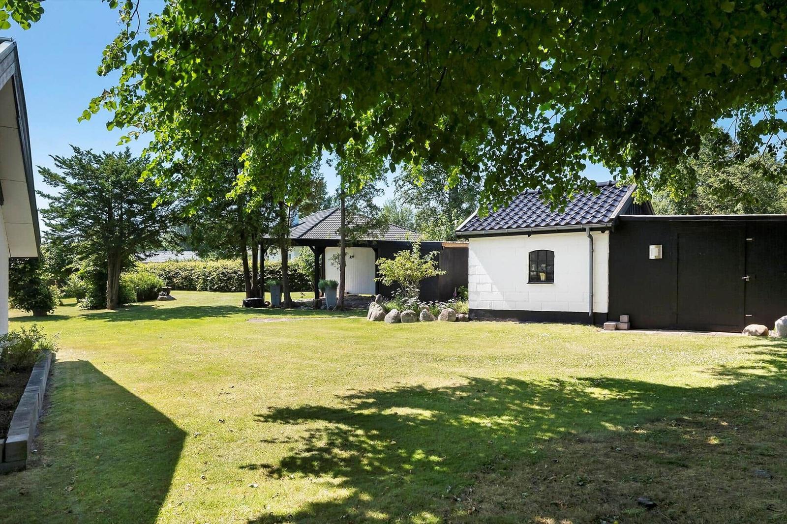 Grüner Garten mit Haus und Pavillon unter Bäumen.
