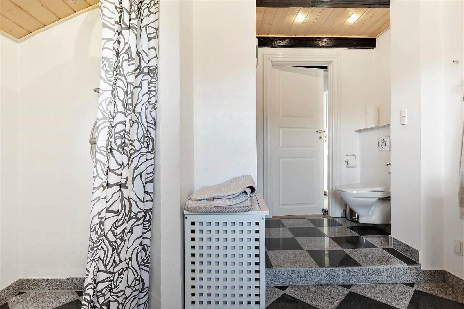 Badezimmer mit Dusche, Toilette und schwarz-weißem Boden
