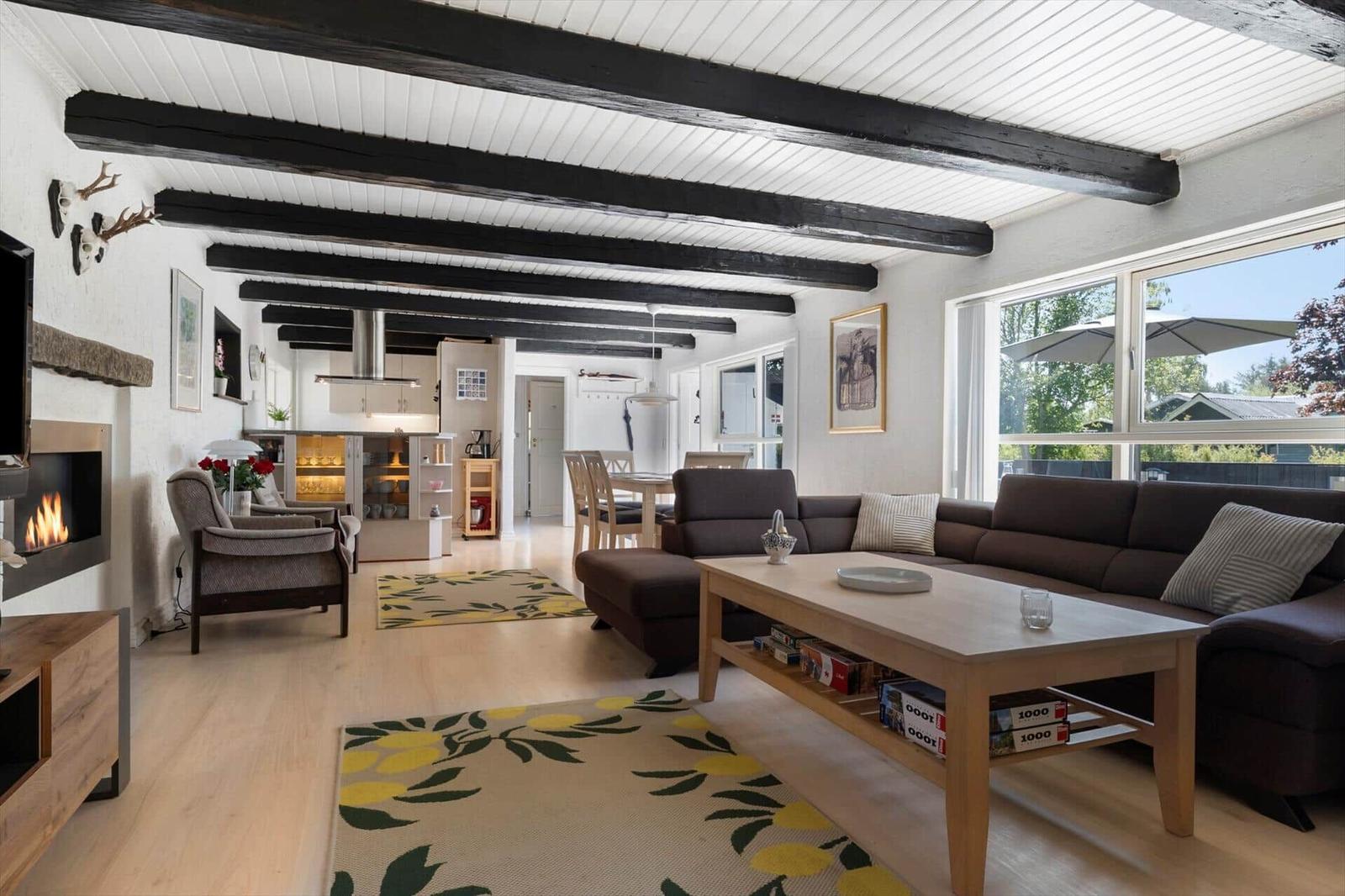 Wohnzimmer mit Sofa, Couchtisch und Kamin. Blick in die Küche und Terrasse.