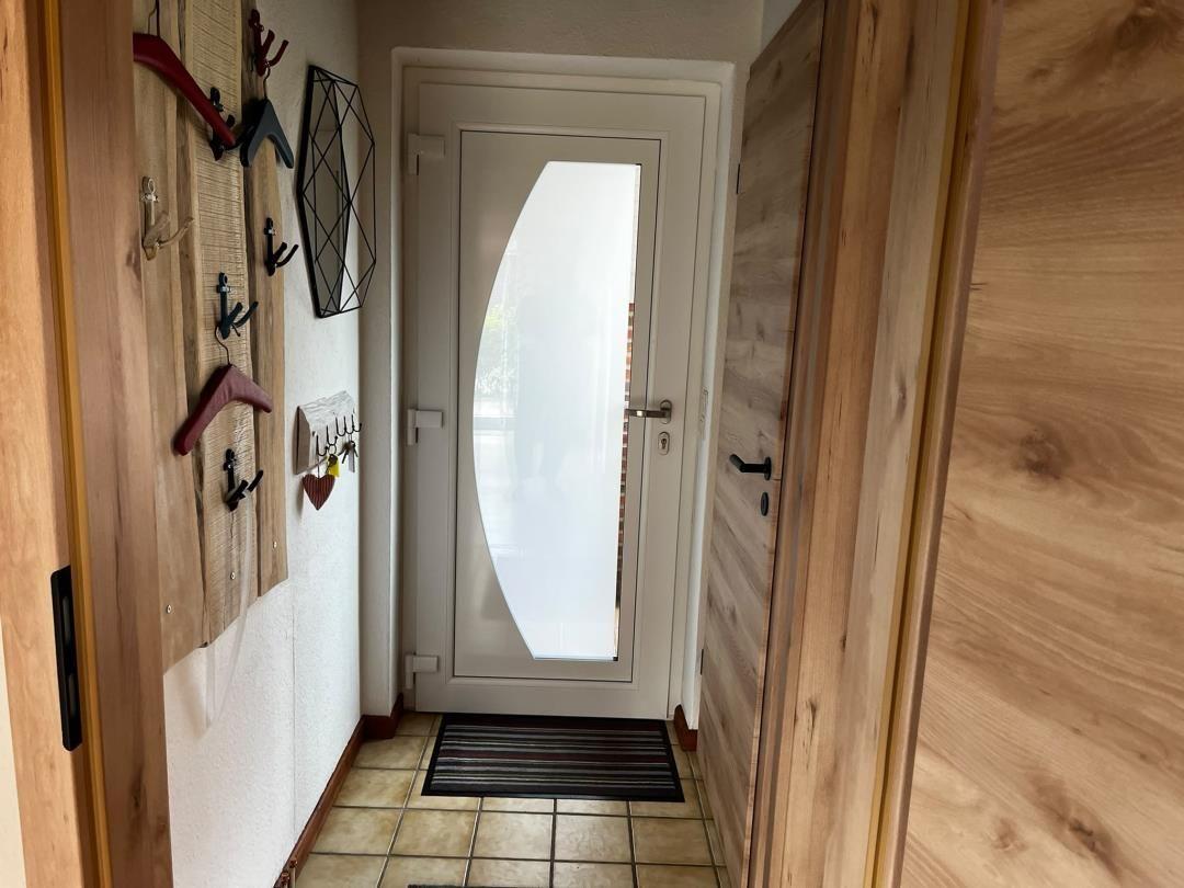 Eingangsbereich mit Holzwand, Haken und Tür mit Glas