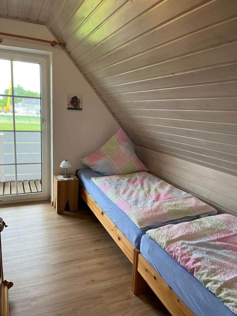 Zimmer mit zwei Betten, Holzdecke und Fenster zur Terrasse.
