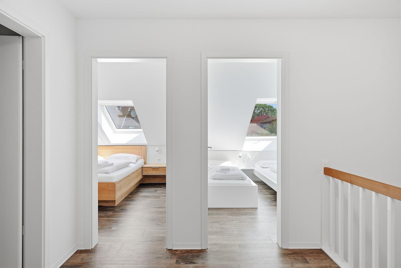 Zwei Schlafzimmer mit Dachfenstern und Holzboden sind über einen Flur erreichbar.