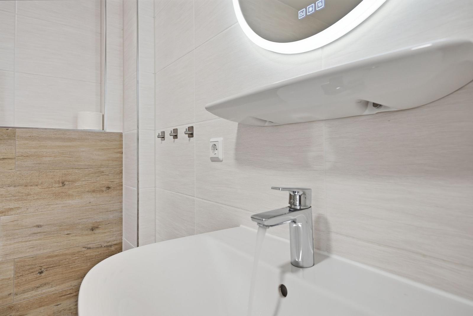Waschbecken mit Wasserhahn, Spiegel und Holzfliesenwand