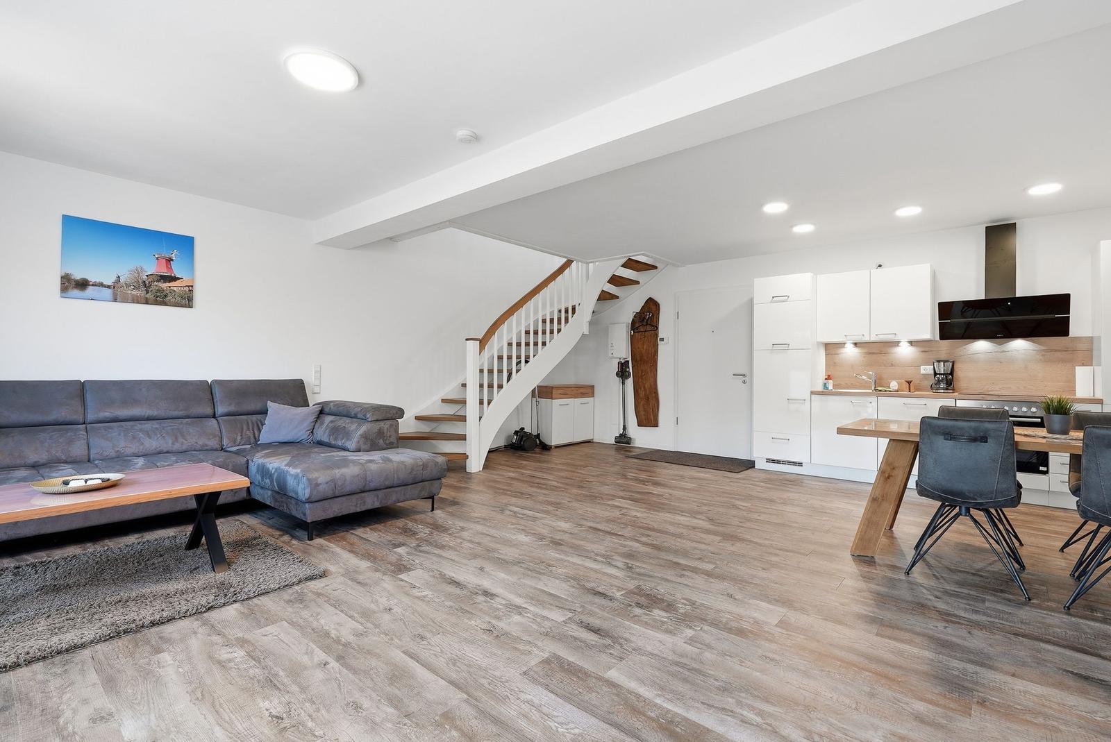 Wohn- und Essbereich mit Küche, Holzboden und Treppe zur oberen Etage.