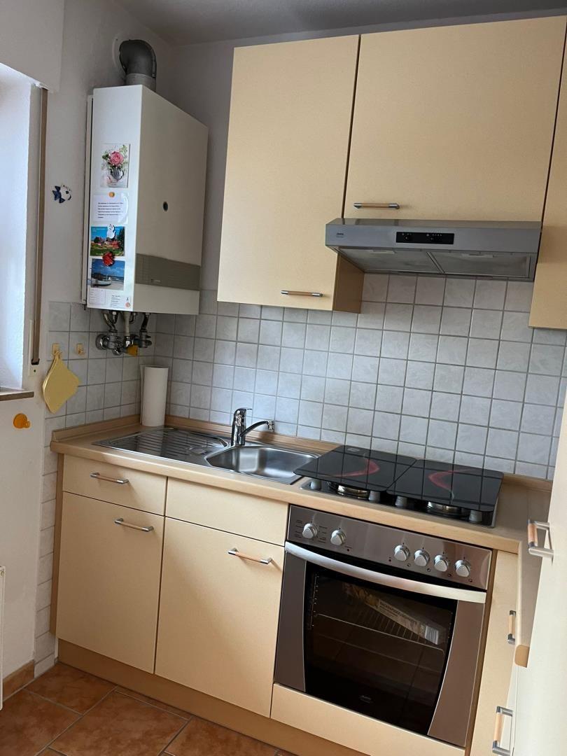 Küche mit Arbeitsplatte, Spüle, Herd und Backofen. Wandfliesen und Holzschrankfronten.