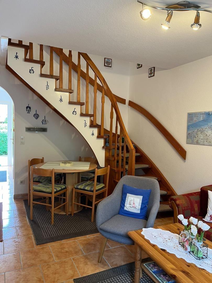 Eingangsbereich mit Holztreppe, Essbereich und Sitzgelegenheiten.