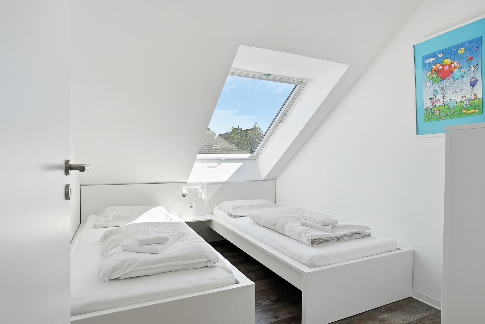 Zimmer mit zwei Betten, Dachfenster und Wandbild