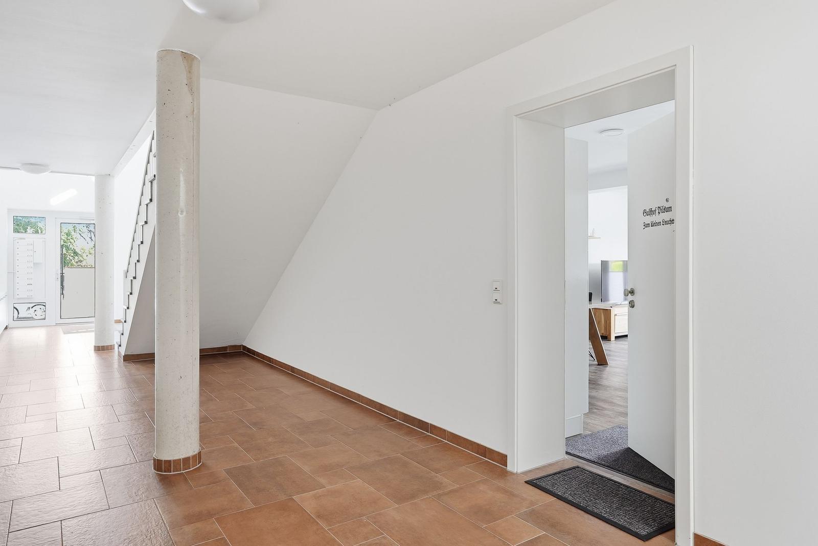 Halle mit Säule, Treppe und Tür zum Wohnbereich.