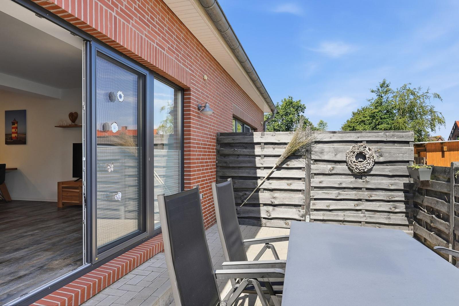 Terrasse mit Tisch und Stühlen, Holzumrandung und Blick ins Haus.