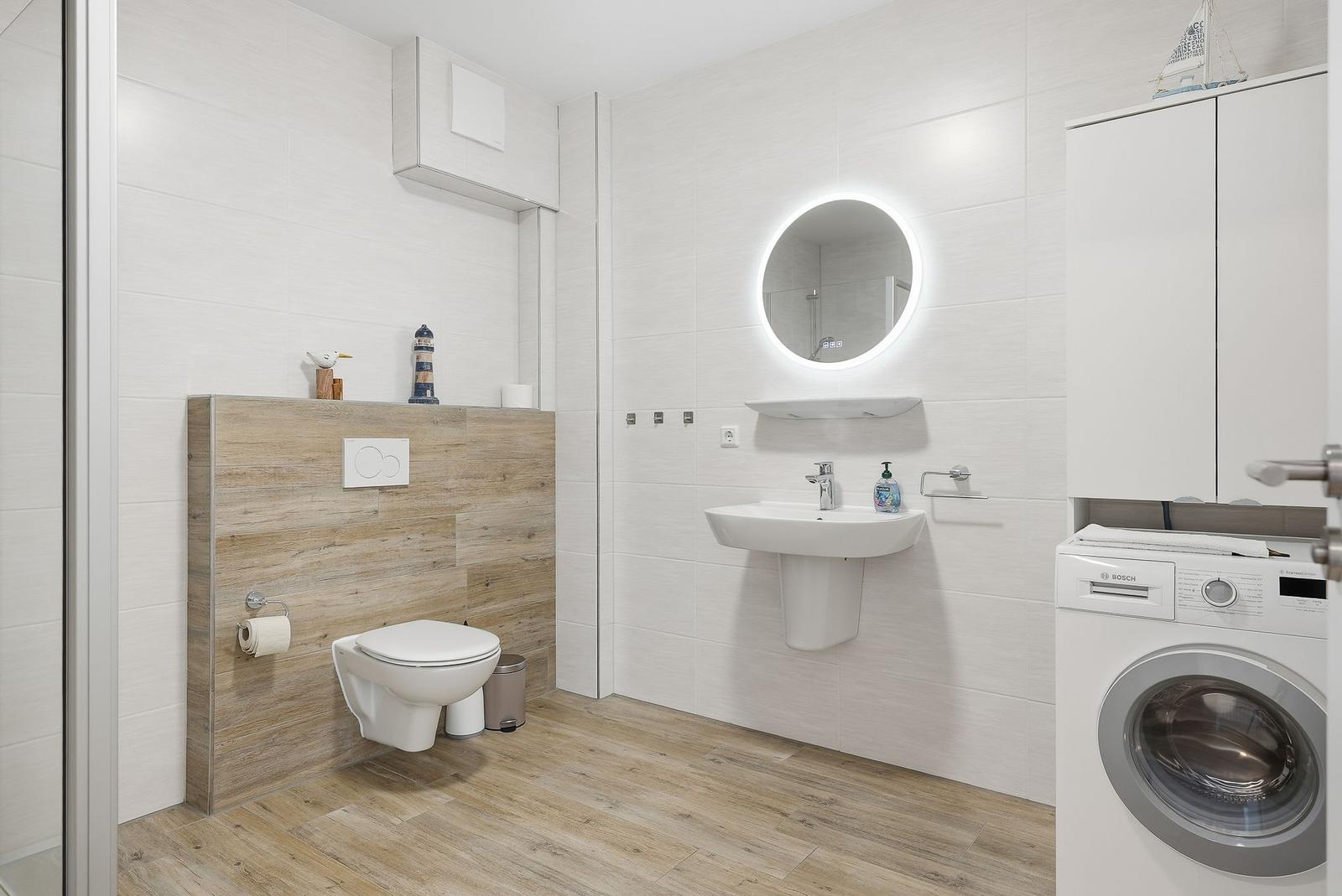Badezimmer mit Toilette, Waschbecken und Waschmaschine