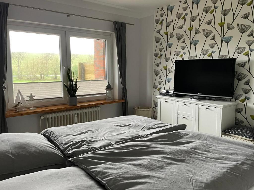 Schlafzimmer mit Bett, TV und Fenster mit Blick auf Grünfläche.
