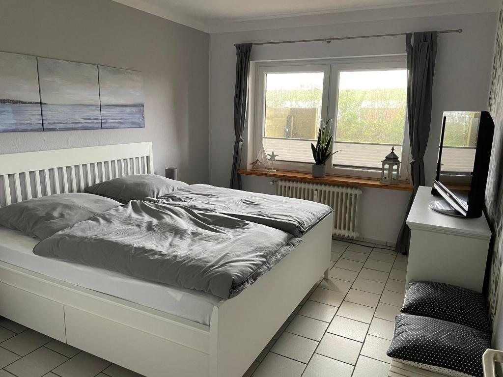 Schlafzimmer mit Doppelbett, Fenster, TV und Pflanze.