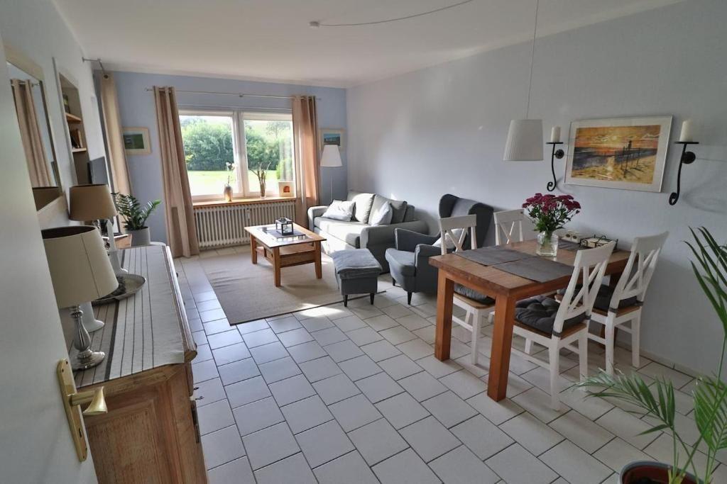 Wohn- und Essbereich mit Sofa, Tisch und Stühlen. Fenster mit Blick auf Garten.