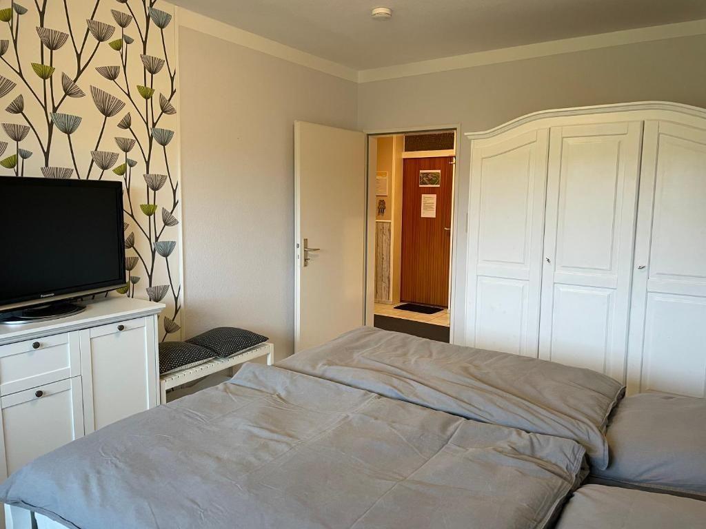 Schlafzimmer mit Doppelbett, Schrank und Fernseher. Wand mit Muster.